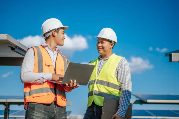 young-asian-technician-man-colleague-safety-uniform-checking-operation-sun-photovoltaic-solar-panel-use-laptop-computer-while-working-solar-farm-scaled